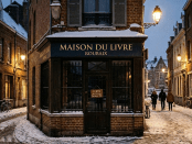 Closed bookstore with snow on the ground and street lamps glowing at dusk