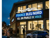 France Bleu Nord radio station building with illuminated sign and people walking outside on a wet street at dusk