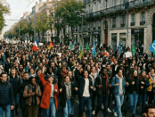 Large crowd of protesters holding signs advocating climate action and social justice in French