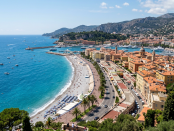 Coastal city with turquoise water, pebble beach, and terracotta-roofed buildings