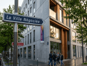 Street sign 'La Ville Négociée' with group of people near modern building