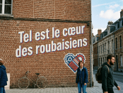 Mural on brick wall reading 'Tel est le cœur des roubaisiens' with gears forming a heart symbol